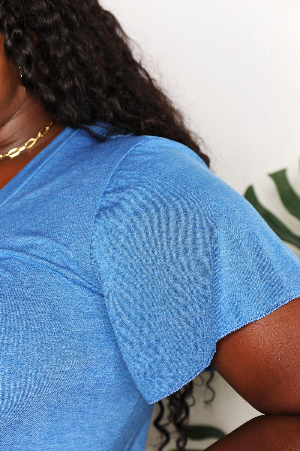 Close-up of a woman wearing a blue short sleeve t-shirt and gold chain necklace