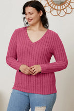 Woman in a pink ribbed long-sleeve V-neck sweater and light blue ripped jeans