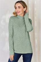 Woman wearing a sage green ribbed knit long sleeve sweater with mock neck